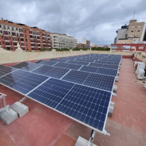 Filas de módulos fotovoltaicos con estructura inclinada sobre la cubierta plana del colegio