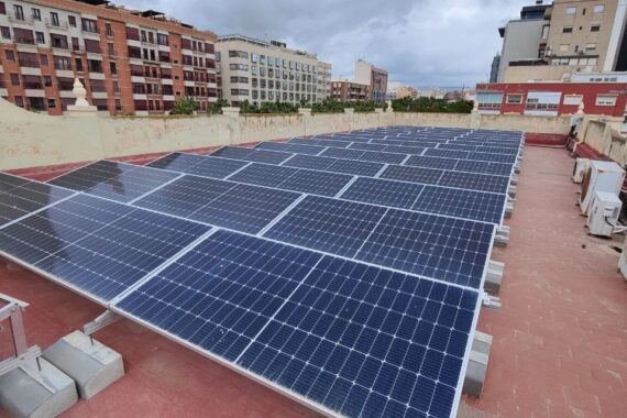 Filas de módulos fotovoltaicos con estructura inclinada sobre la cubierta plana del colegio