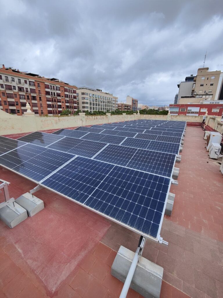 Filas de módulos fotovoltaicos con estructura inclinada sobre la cubierta plana del colegio Filas de módulos fotovoltaicos con estructura inclinada sobre la cubierta plana del colegio