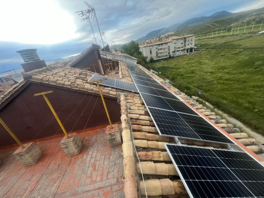 Fila de módulos solares sobre la cubierta inclinada del edificio residencial Fila de módulos solares sobre la cubierta inclinada del edificio residencial