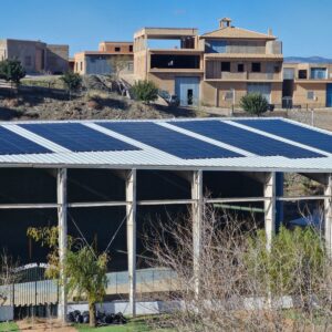 Cubierta fotovoltaica sobre la estructura de un frontón municipal con el pueblo de montaña al fondo