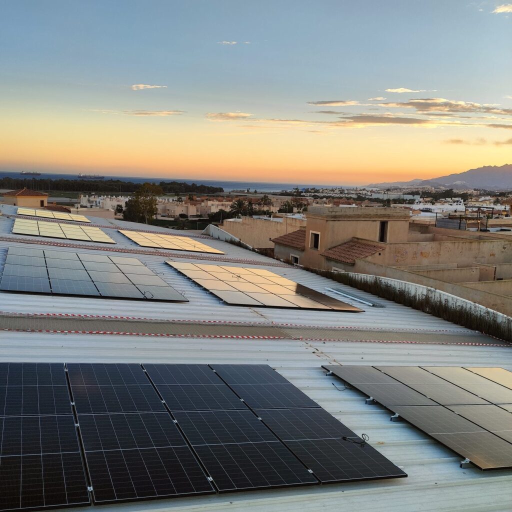 Módulos fotovoltaicos sobre la cubierta de un pabellón deportivo municipal al atardecer Módulos fotovoltaicos sobre la cubierta de un pabellón deportivo municipal al atardecer