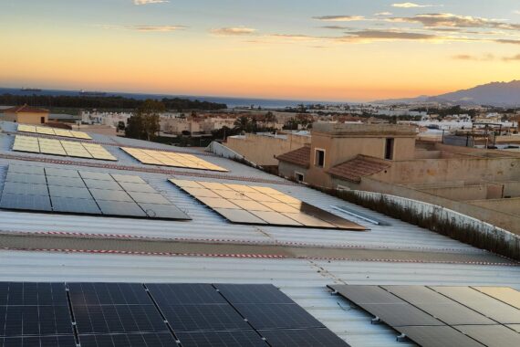 Módulos fotovoltaicos sobre la cubierta de un pabellón deportivo municipal al atardecer Módulos fotovoltaicos sobre la cubierta de un pabellón deportivo municipal al atardecer
