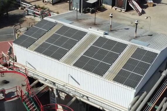 Vista aérea de nave industrial con campo fotovoltaico en cubierta