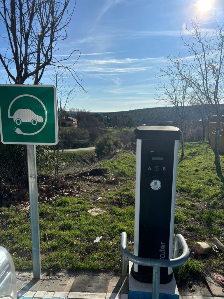 Punto de recarga para vehículo eléctrico con señalización junto a zona verde Punto de recarga para vehículo eléctrico con señalización junto a zona verde