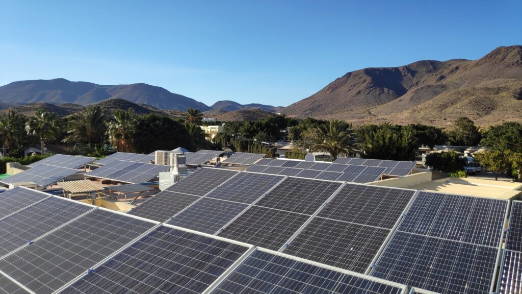 Campo fotovoltaico sobre las cubiertas de un camping entre palmeras y la sierra de Cabo de Gata Campo fotovoltaico sobre las cubiertas de un camping entre palmeras y la sierra de Cabo de Gata
