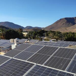 Campo fotovoltaico sobre las cubiertas de un camping entre palmeras y la sierra de Cabo de Gata