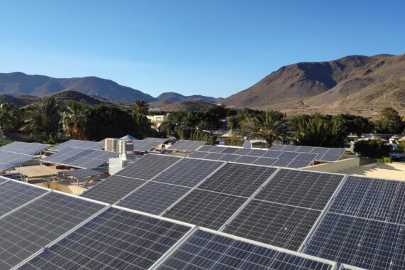 Campo fotovoltaico sobre las cubiertas de un camping entre palmeras y la sierra de Cabo de Gata