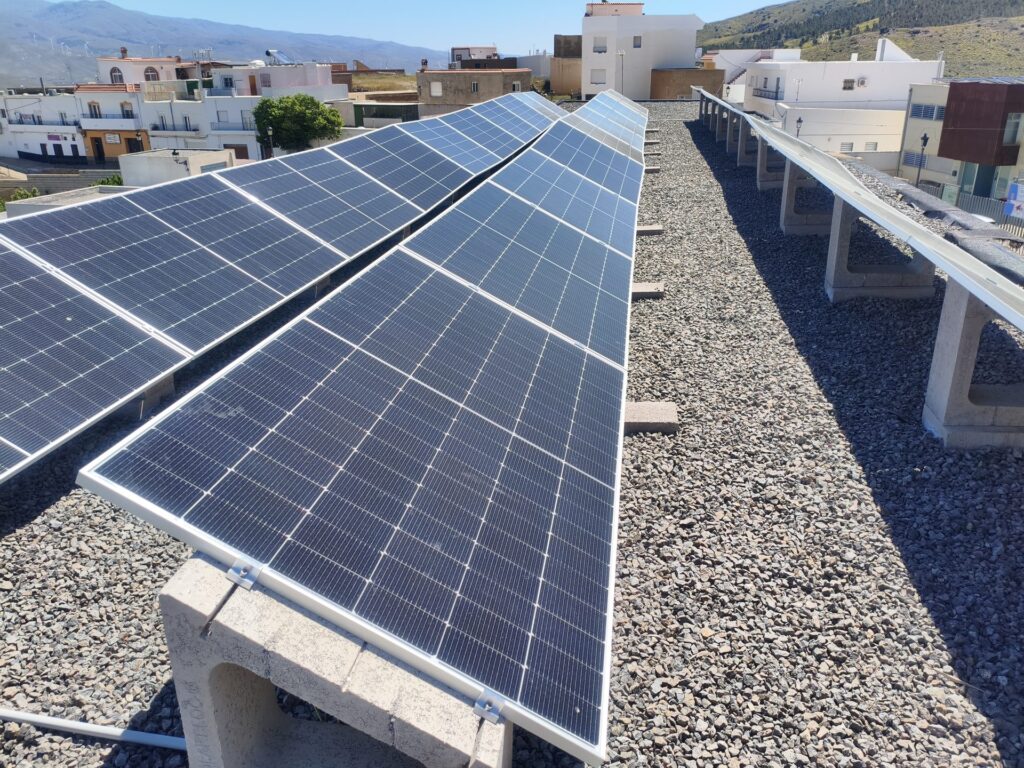 Filas de módulos fotovoltaicos sobre cubierta de grava del centro educativo Filas de módulos fotovoltaicos sobre cubierta de grava del centro educativo